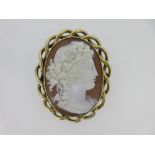 A shell cameo brooch depicting a Bacchante, the girl in profile with an ornate wreath of vine leaves