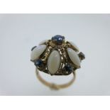 An opal and sapphire flowerhead cluster ring, the central round facetted sapphire with six