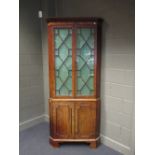 A George III period mahogany corner cupboard with dentil cornice, the upper part enclosed by a