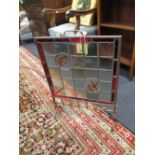 A Victorian brass framed fire screen inset with stained glass panels