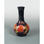 A Moorcroft Pomegranate pattern bottle vase, the fruits painted to a deep blue ground, painted and