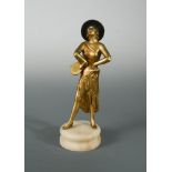 An Art Deco gilt and patinated spelter model of a female tambourine player, raised on a circular