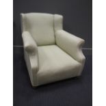 An Edwardian wing-back lounging chair, re-upholstered in pale green linen and raised on turned