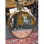 A mahogany and parcel gilt oval wall mirror, with eagle battle trophy cresting, 98cm high