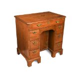 A George III 'red walnut' kneehole desk, with re entrant corners, seven drawers, a blind drawer