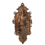 A large 19th century carved Black Forest wall plaque, carved with dead game, horn, musket and game
