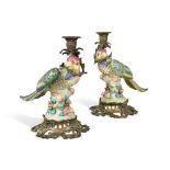 A pair of gilt metal mounted porcelain parrot candlesticks, with applied floral rock work bases with