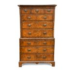 A George I walnut chest on chest, with mirrored veneers and feather banded borders, canted moulded