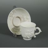 A Saint-Cloud blanc de chine trembleuse cup and saucer, circa 1720-40, with moulded and applied