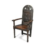 A 17th century oak 'Cacqueteuse' wainscote armchair, with rosette, scroll and other carved
