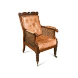 A Regency mahogany bergere library armchair, with shell and scroll carved crest rail, buttoned tan