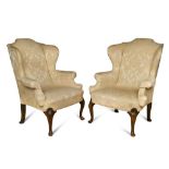 A pair of Queen Anne style chairs, upholstered in a cream damask fabric, on shell carved cabriole