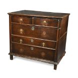 A 17th century oak chest of two short and three long drawers, having brass drop handles, on stile