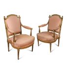 A pair of Louis XVI style carved gilt wood armchairs, upholstered in pink fabric on fluted legs (