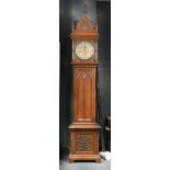 A late Victorian Gothic carved oak chiming longcase clock, the hood with arched pediment having