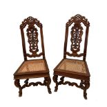 A pair of carved high back hall chairs, with caned seats, on shaped legs (2) 117cm (46in) high