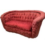 A sofa of concave outline, button upholstered in a dark crimson silk damask fabric, with a loose
