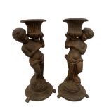 A pair of cast iron figural jardiniere, each child figure holding an urn aloft (2) 84cm (33in)