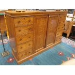 A Victorian satinwalnut dwarf cupboard, with two banks of drawers flanking two cupboard doors