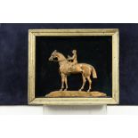 A gilded cast metal relief of a racehorse and jockey, mounted in a velvet lined frame, 21cm (8in)