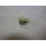 A three stone cross over style diamond set ring stamped '18ct plat'