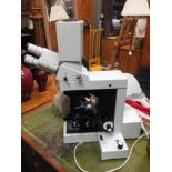 A Swift and Son binocular compound microscope with circular stage No 25947, and an electric