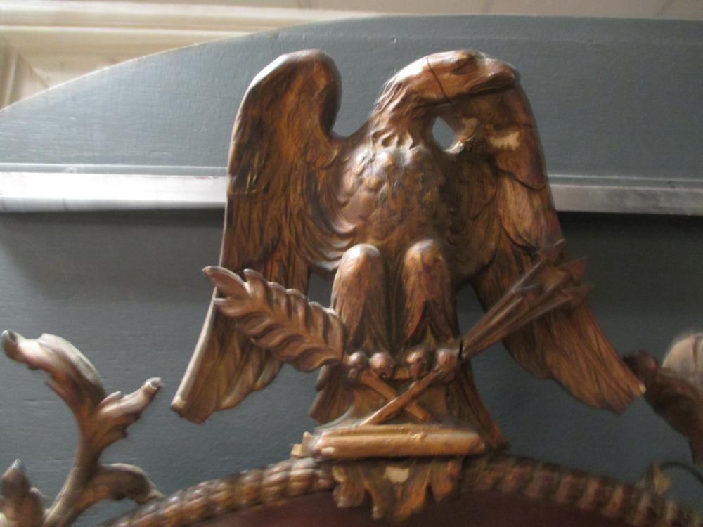 A mahogany and parcel gilt oval wall mirror, with eagle battle trophy cresting, 98cm high - Image 2 of 3