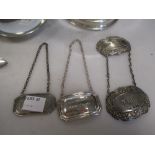 A collection of silverware including four decanter labels, a pusher, a butter knife, a two handled