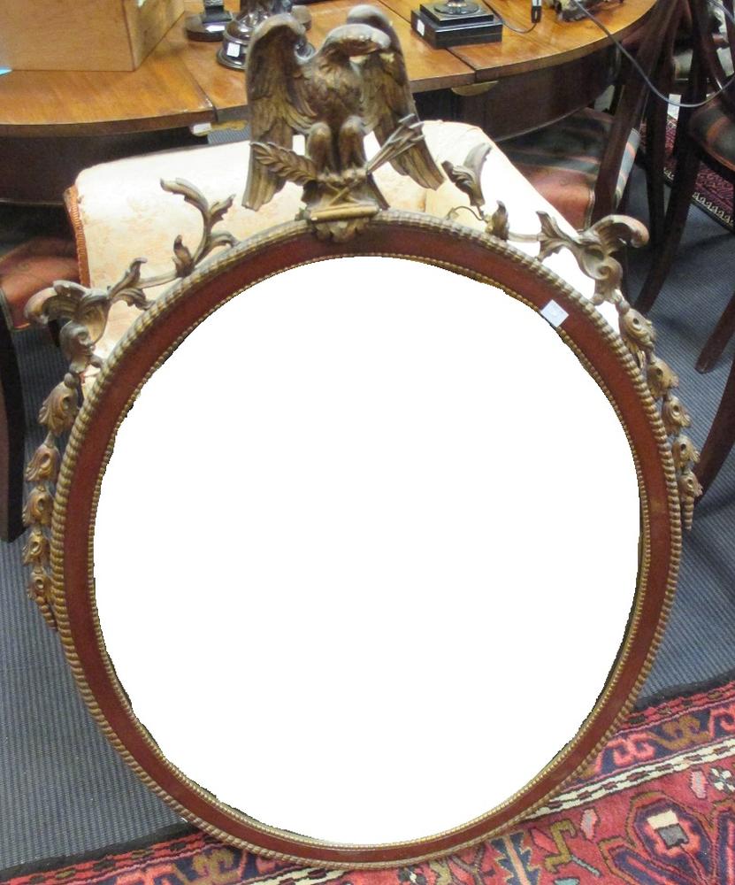 A mahogany and parcel gilt oval wall mirror, with eagle battle trophy cresting, 98cm high