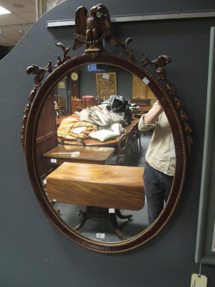 A mahogany and parcel gilt oval wall mirror, with eagle battle trophy cresting, 98cm high - Image 3 of 3