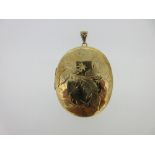 A 9ct gold engraved locket, the large oval engraved on both sides with swirling stems, leaves and