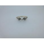 A diamond and pearl three stone ring, the 4.6mm pearl peg set between two old cushion cut and claw