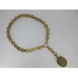 A late 19th century bar and hoop link collar suspending a cast locket, of unhallmarked gilt metal,