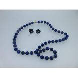 A lapis lazuli bead necklace together with a pair of carved lapis flowerhead earstuds, the