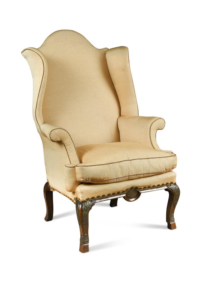 A Queen Anne walnut and brass mounted wing back armchair, the apron centred by an embossed brass