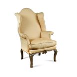 A Queen Anne walnut and brass mounted wing back armchair, the apron centred by an embossed brass