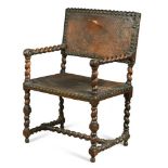 A late 17th century walnut framed armchair, the twist carved frame with leather brass nailed back