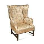 A 19th century wing armchair, upholstered in a Chinese silk fabric, on square tapering stretchered