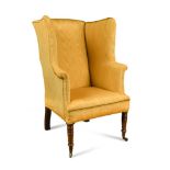 A Regency mahogany framed wing armchair, upholstered in a canary yellow satin fabric, on turned legs