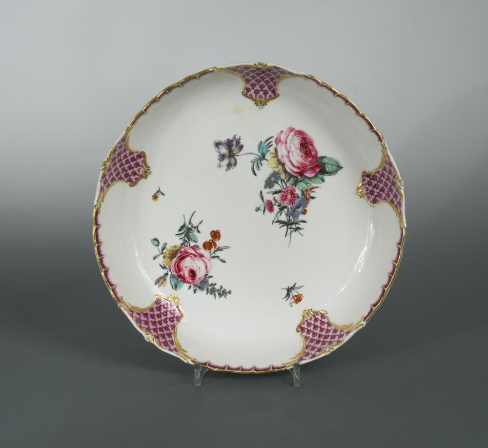 A Tournai dish, circa 1780, painted to the centre with scattered floral bouquets within puce trellis