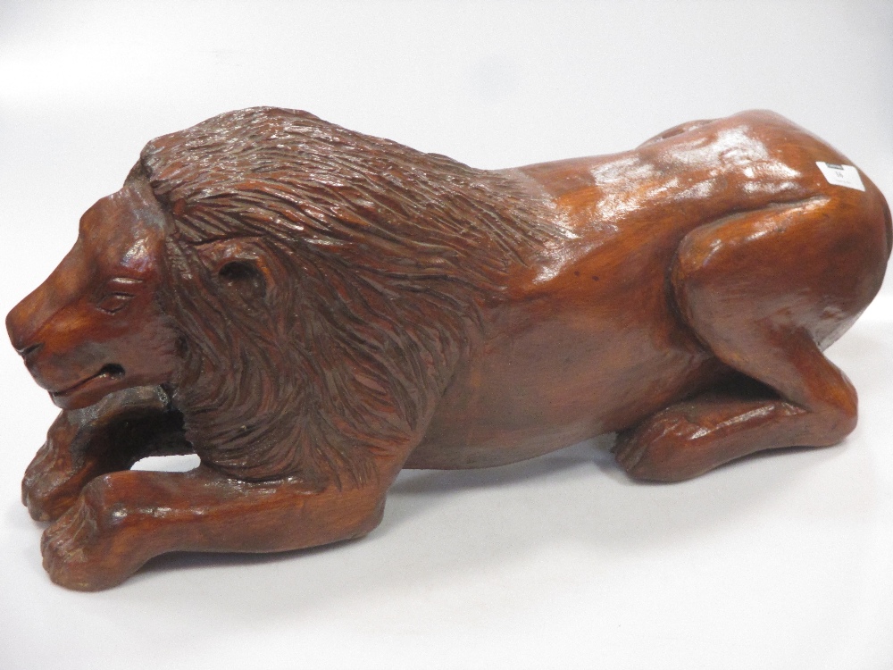 A carved and stained pine model of a recumbent lion, 59 cm wide