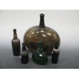 A group of glass bottles: A carboy of olive/brown glass 41cm high. A German green glass flask with