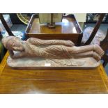 A carved and red stained wood figure of a reclining Buddha, 61cm wide
