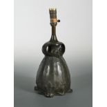 An Art Nouveau bronzed metal table lamp, the pear shaped base with twin-handles and cast with