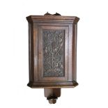 An Arts & Crafts oak hanging corner cupboard, the panel door carved with fruiting vines 111 x