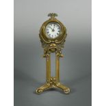 An Art Nouveau brass desk clock by the British United Clock Co., the enamelled dial above a female