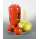 Four Burmantofts faience vases, comprising a yellow glaze bottle vase, a large red glaze vase, and
