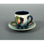 A Moorcroft Leaves and Berries coffee can and saucer, painted to a pale green ground, impressed