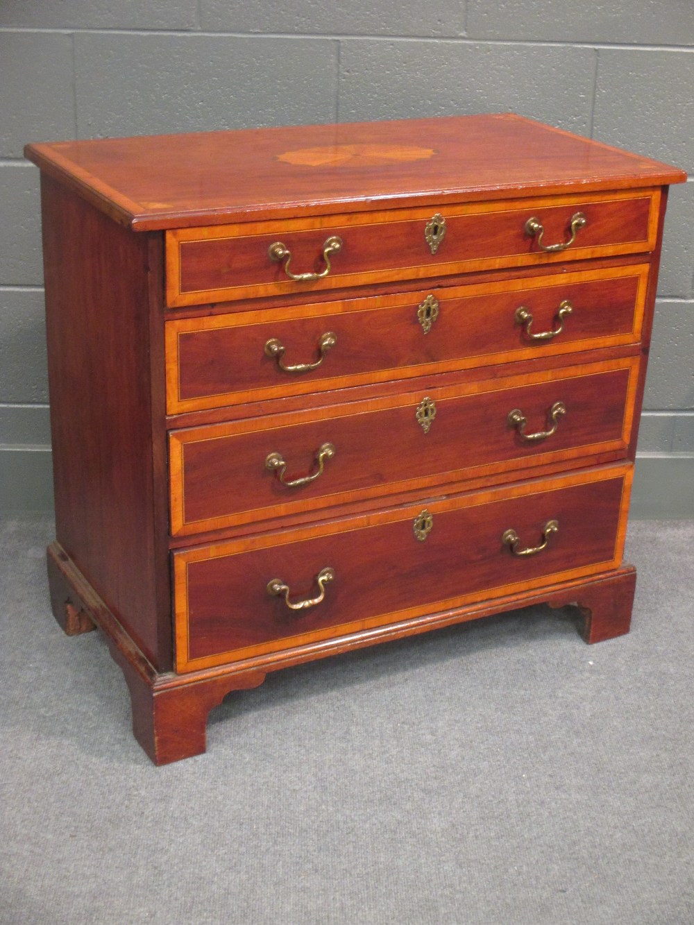 A George III mahogany and crossbanded chest of four long graduating drawers on bracket feet 79 x