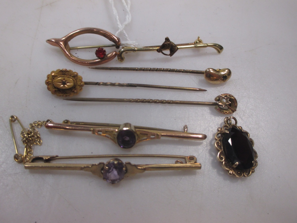 A 9ct gold horse and riding crop brooch together with two amethyst bar brooches, a garnet pendant